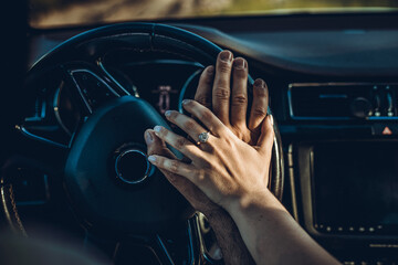 Close up shot of loving couple traveling by car and holding hands. Summer background. Focus on hands of man and woman in a road trip.