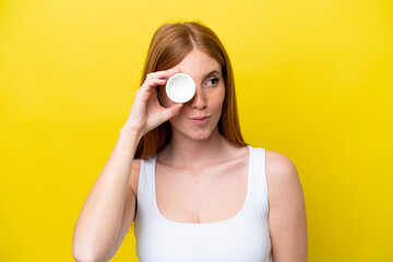Young redhead woman isolated on yellow background with moisturizer