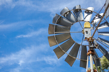 Aluminium silver circle wind turbine with blue sky in a background.