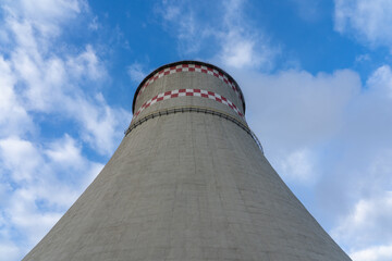 Thick smoke from one large chimney against the blue sky. Heating season.