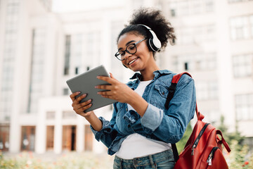 Happy Black Female Student Using Tablet Computer Wearing Headphones Outside