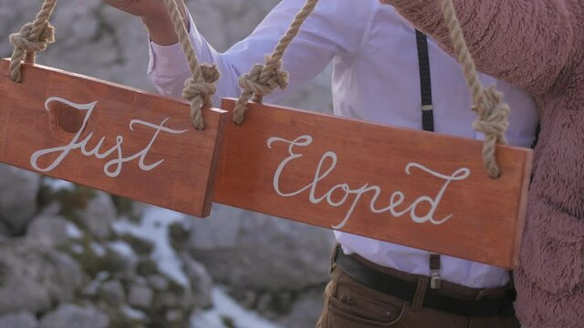 just eloped couple hold wooden sings in hands on mountain elopement, closeup
