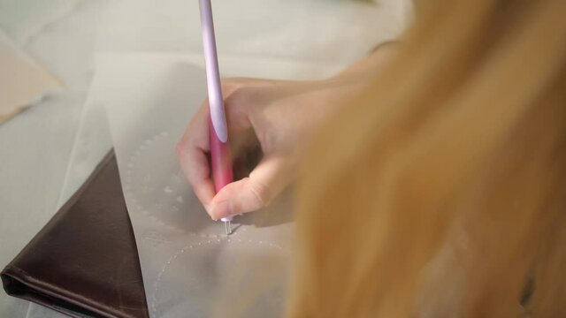 young blonde woman doing pergamano craft with pink pen, closeup slow motion topdown