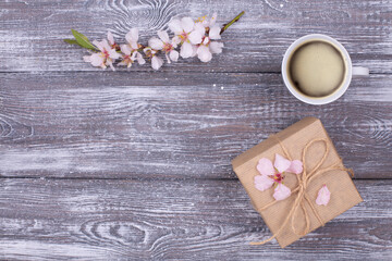 Spring composition with coffee, a gift wrapped in craft paper, spring blossoming almond branches...