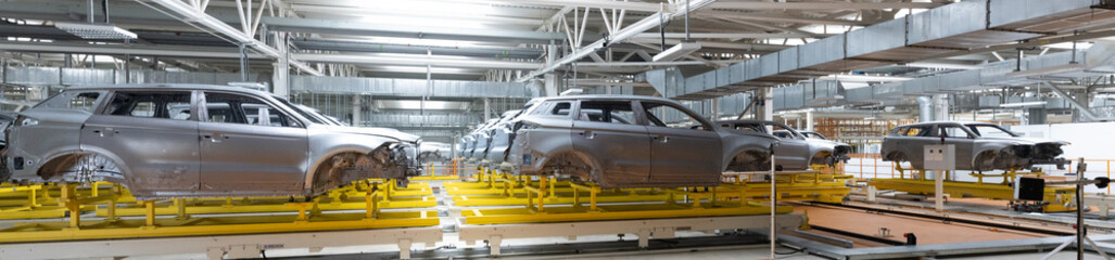 Panoramic photo of car bodies are on assembly line. Factory for production of cars. Modern automotive industry