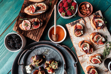 Set Bruschettas with figs and goat cheese, Blue cheese and nuts, onion jam, fresh thyme, honey on grilled crusty bread on black metal tray, flat lay, top view