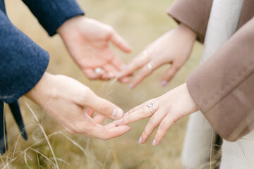 man and woman touch hands with each other and take hands. Autumn walk of a couple in nature in wool coats. Visualization of caring and relating to each other. Traditional sexual relationship.
