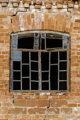 Wooden window frame with broken glass in the wall of an abandoned brick building. The picture was taken in the village of Pervokrasnoe, in the Orenburg region