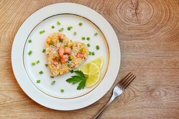 Heart shaped salmon fried rice,jasmine rice with smoked salmon,garlics,onions,spring onions,eggs and soy sauce on plate with wooden background.Love healthy food concept for Valentine's day.Top view