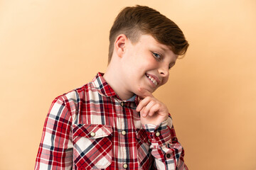 Little redhead boy isolated on beige background