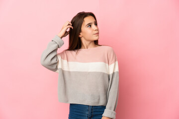 Little girl isolated on pink background having doubts while scratching head