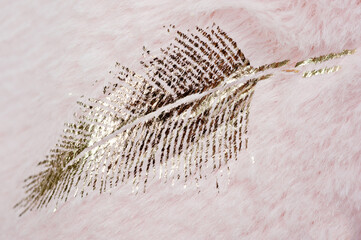 Print in the form of a golden feather on the surface of faux fur in pink.