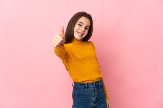 Little girl isolated on pink background with thumbs up because something good has happened