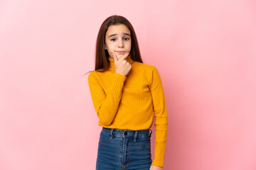 Little girl isolated on pink background having doubts