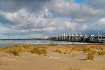 View across the sea to the Eastern Scheldt Storm Surge Barrier in Zeeland with a stormy sky,...