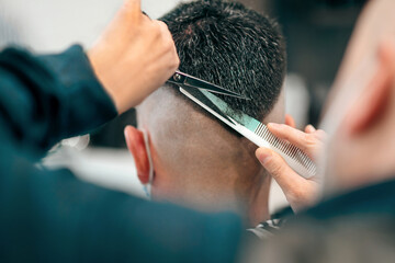 Professional barber using scissors and comb to cut a mans hair