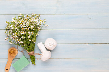 Sea salt, aromatherapy oil in bottles and chamomile on vintage wooden background.