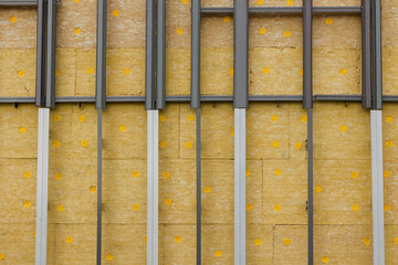 Metal profiles of the hinged facade fastening system. Front view. Installation of thermal insulation boards in a checkerboard pattern