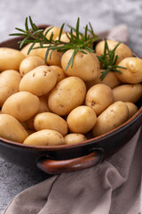 Raw small potatoes in a cast iron skillet on a beton background.