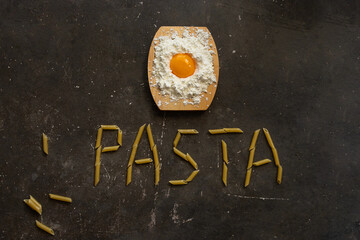 Cooking Italian macaroni concept. Two ingredients eggs and wheat flour with PASTA word made with...