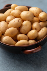 Raw small potatoes in a cast iron skillet on a beton background.