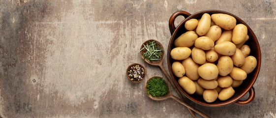 Raw small potatoes in a cast iron skillet on a beton background.