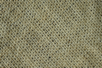 A piece of burlap fabric lies on the table at an angle. Flat lay, top view, close up, macro