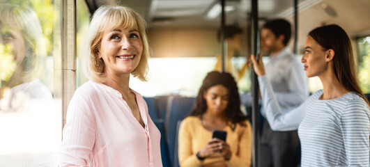 Beautiful smiling mature woman taking bus, looking out of window © Prostock-studio