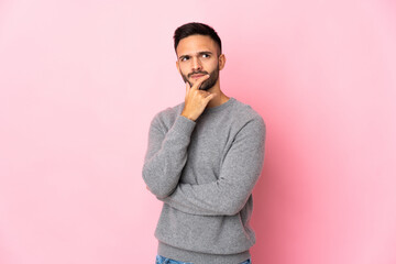 Young caucasian man isolated on pink background having doubts and with confuse face expression