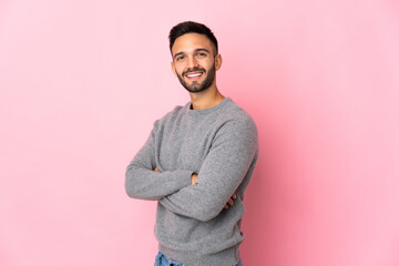 Young caucasian man isolated on pink background with arms crossed and looking forward
