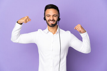 Naklejka premium Telemarketer man working with a headset isolated on purple background doing strong gesture