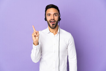 Telemarketer man working with a headset isolated on purple background intending to realizes the solution while lifting a finger up