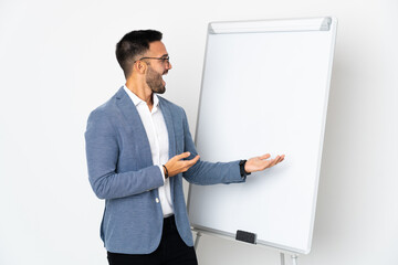 Young caucasian man isolated on white background giving a presentation on white board and with surprise expression