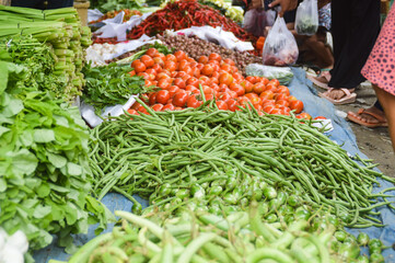 Fresh produce displayed at a local market with buyers passing by and hunting for cheaper price to...