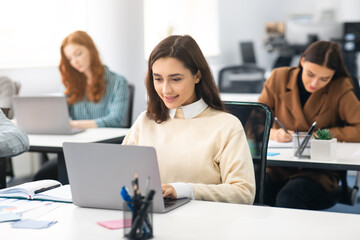 Portrait of female student using laptop in classroom