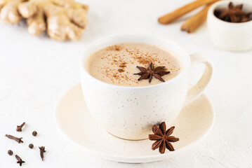Indian vegan masala chai with coconut milk, anise, cinnamon, ginger, pepper in a mug on the table.