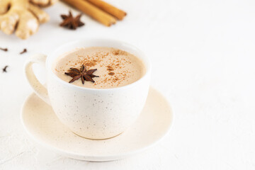 Indian masala tea with coconut milk, anise, cinnamon, ginger, pepper in a mug on the table. Selective focus. Horizontal orientation, copy space.