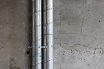 Ventilation pipes in silver insulation material inside new building.