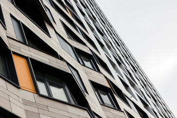 The exterior wall of a contemporary commercial style building with aluminum metal composite panels and glass windows. The futuristic building has engineered diagonal cladding frame panels.