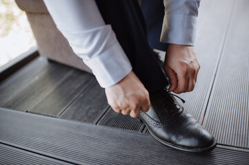 A man in a suit, the groom, close-up puts on shoes, ties his shoelaces
