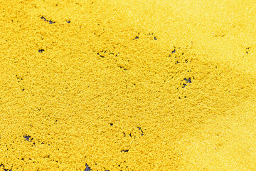 Rubber coating for playgrounds. Hot yellow rubber granules with adhesive lie on the surface and are ready to be applied and compacted PDM rubber granules. Floor covering for sports. Selective focus.
