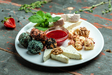Cheese Assortment plate served with with jam, nuts and fresh mint. craft sheep goat cheese on a wooden background, vertical image. top view. place for text