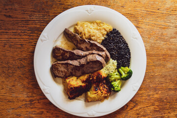 Top view of a plate of beef steak slices with sauerkraut, lentils and brussel sprouts for high protein ketogenic meal 