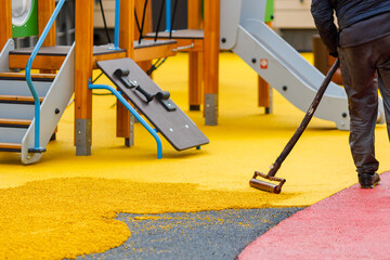 Laying a rubber coating of crumbs on a children's playground. Roller leveling rubber mulch.