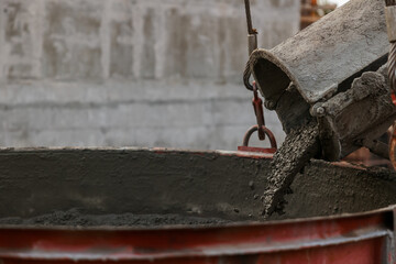 Industrial construction machinery workers pouring cement concrete using a concrete bucket. Concrete...