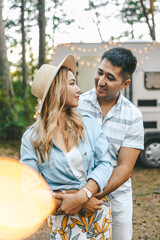 Married Asian man and woman in love travel together on a road trip on a camper in the woods in summer in nature on a romantic honeymoon outdoors. Selective focus