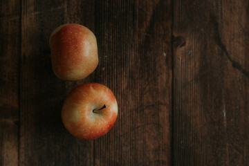 Two ripe apples lie on a wooden table. Homemade apples on a wooden background. Space for text. View from above