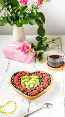 S.Valentine's Day breakfast concept. Mix of berries in a heart shaped bowl, yogurt, tea, roses and gift
