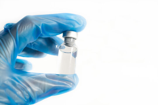 Vaccination concept. COVIC-19 cororavirus vaccine. The doctor's hands with blue gloves hold the vaccine bottle, on a white background.