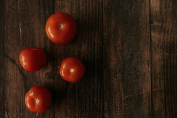 Four ripe red tomatoes lie on a wooden table. Tomatoes on a wooden background. Selectiv focus. View from above